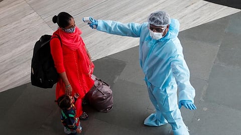 A health worker in personal protective equipment (PPE) checks the temperature of a passenger at a railway station, amid the spread of the coronavirus disease (File photo)