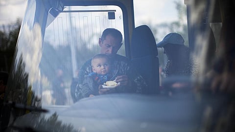 A man feeds a child as they arrive by bus at a reception center for displaced people in Zaporizhzhia, Ukraine (Photo: AP)