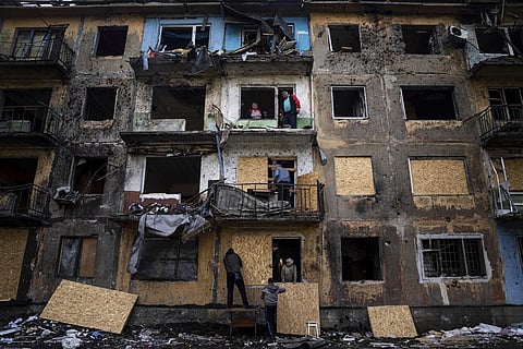 Local residents close the windows of an apartment building with plywood after Russian shelling in Dobropillya
