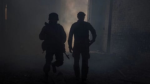 Ukrainian service members walk in the industrial area of the city
