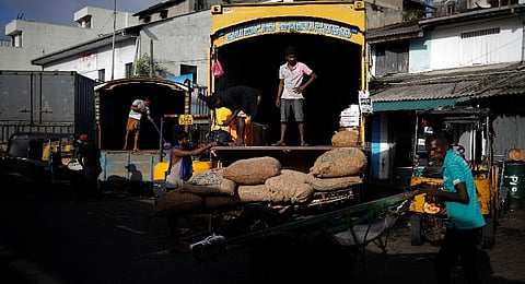 Laborers wait after unloading the sacks of rice at a wholesale market