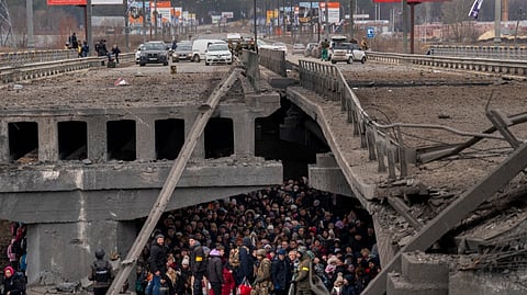 Ukrainians crowd under a destroyed bridge