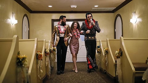 Elvis impersonator Brendan Paul, right, walks down the aisle during a wedding ceremony for Katie Salvatore, center, and Eric Wheeler at the Graceland Wedding Chapel in Las Vegas.