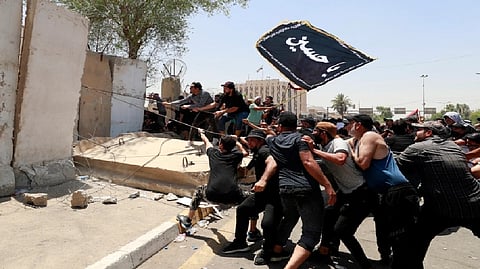 Supporters of the Iraqi cleric Moqtada al-Sadr bring down concrete barriers leading to the capital Baghdad's high-security Green Zone