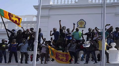 Sri Lankan protesters, some carrying national flags, stand on top of prime minister Ranil Wickremesinghe's office