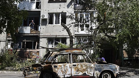 A destroyed car lies next to an apartment building damaged