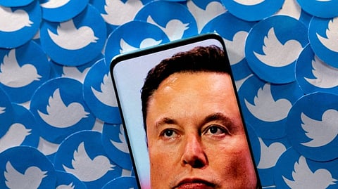 An image of Elon Musk is seen on smartphone placed on printed Twitter logos in this picture illustration