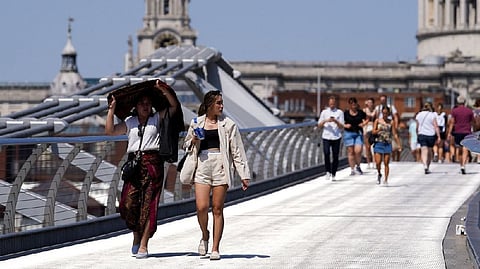 People cover themselves from the sun at Millennium Bridge during a heatwave in London