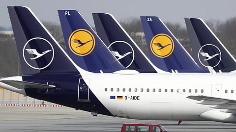 German Lufthansa planes sit parked in a line at the airport