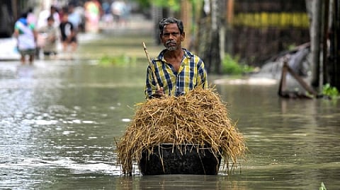 A man carries fodder for his livestock as he wades through flood water in Solmara.