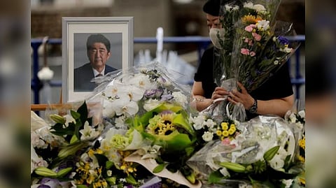 A mourner offers flowers next to a picture of late former Japanese Prime Minister Shinzo Abe