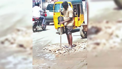 Worker fills debris in one of the potholes.