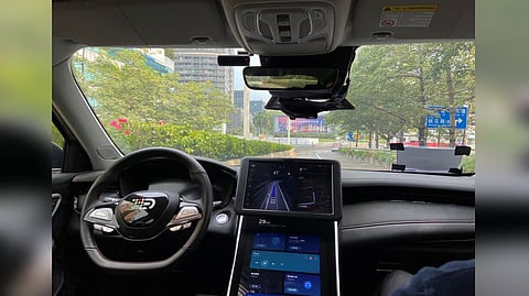 A safety driver sits on the passenger seat as the car with autonomous driving system