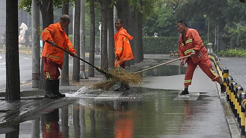 Workers clear a puddle of water after a rainstorm
