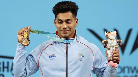 Gold Medallist India's Achinta Sheuli celebrates on the podium during the medal ceremony.