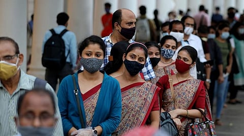 People in New Delhi wearing protective face masks stand in a line to enter a metro station amidst the spread of the coronavirus