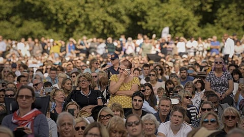A woman wipes away tears as she joins people sitting in Hyde Park