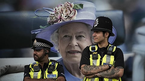 Police officers are backdropped by a photograph of Queen Elizabeth II in London, Friday, Sept.16, 2022. The Queen will lie in state in Westminster Hall for four full days before her funeral on Monday.