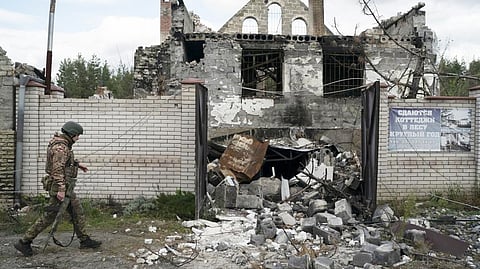 A Ukrainian serviceman from Dnipro-1 regiment walks past a damaged building in the retaken village of Shchurove, Ukraine, Sunday, Sept. 25, 2022.