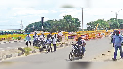 Riders carrying their vehicles, after the entry was blocked, to the service road even as policemen are posted on duty at NH intersection in Vellore on Monday.