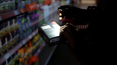 A shopper uses a torch to see products in a supermarket