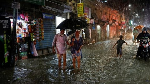 People wade through a flooded street amid continuous rain before the Cyclone Sitrang hits the country in Dhaka.