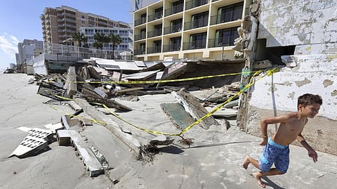 A boy runs past a collapsed pool deck Monday, Oct. 3, 2022, in Daytona Beach Shores, Fla., as hotel and condo seawalls and decks along the Volusia County coastline were gutted by Hurricane Ian last week.