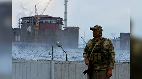 A serviceman with a Russian flag on his uniform stands guard near the Zaporizhzhia Nuclear Power Plant in the course of Ukraine-Russia conflict outside the Russian-controlled city of Enerhodar in the Zaporizhzhia region