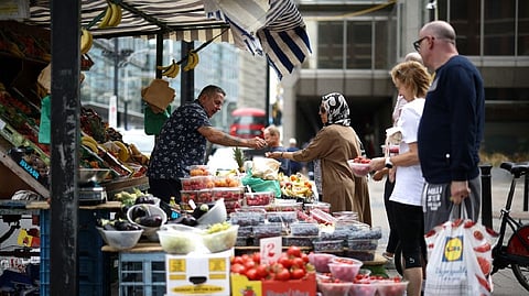 A person buys produce from a fruit and vegetable market stall in central London