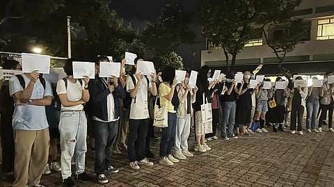 Protesters hold up blank white papers during a commemoration for victims of a recent Urumqi deadly fire at the Chinese University of Hong Kong in Hong Kong