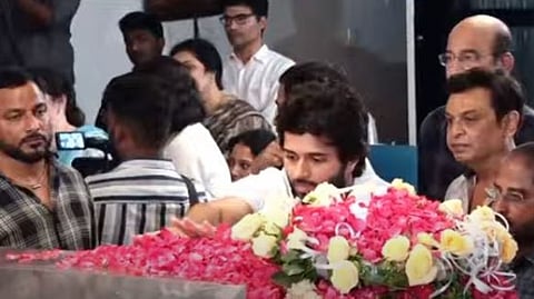 Actor Vijay Devarakonda offering flowers to late Krishna Garu's mortal remains.