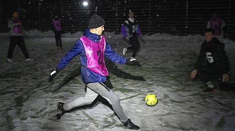Men take part in a soccer game during a blackout in Irpin
