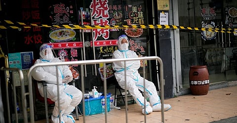 Workers in protective suits keep watch behind a barrier at a sealed restaurant area