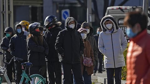 Residents stand in line for their routine COVID-19 tests in the freezing cold weather near the site of last weekend's protest in Beijing, Wednesday, Nov. 30, 2022.