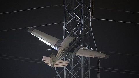 A small plane rests on live power lines after crashing, Sunday, Nov. 27, 2022, in Montgomery Village, a northern suburb of Gaithersburg, Md.