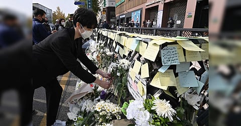 A mourner lays flowers at a makeshift memorial for the victims of the deadly Halloween crowd surge