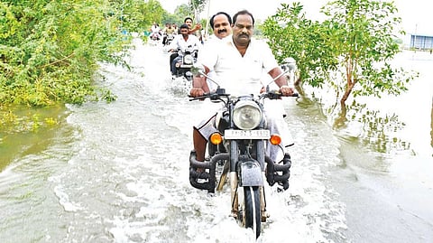 Minister Siva V Meyyanathan inspecting flood-hit areas by riding on bike in Mayiladuthurai on Saturday.