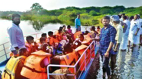 Students and villagers being ferried in the mechanised boat across flooded Kanthayar River in Erode on Wednesday.
