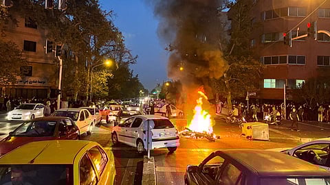 A police motorcycle burns during a protest over the death of Mahsa Amini