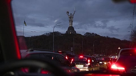 Cars move in the dark, with the Motherland Monument in the background, during a blackout in Kyiv, Ukraine.