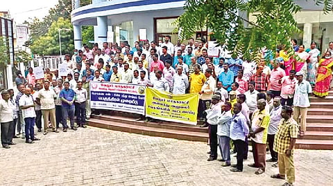 Corporation workers staging a silent protest in front of the urban body premises in Vellore on Thursday.