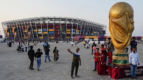 People pose for pictures next to a replica of the World Cup Trophy, right, with the Stadium 974 in the background before the Qatar Fashion United event in Doha, Qatar.