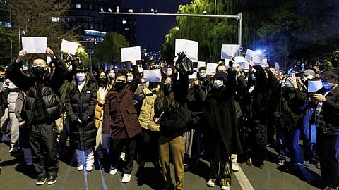 People gather for a vigil and hold white sheets of paper in protest over coronavirus disease (Covid-19) restrictions