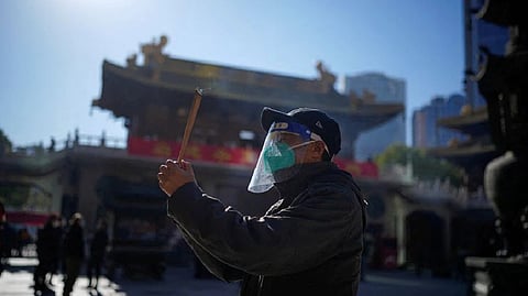 Man praying at a Buddhist temple wearing a mask