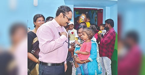 A child trying its hand at checking on Collector Dr Alby John Varghese with stethoscope at the upgraded children?s centre in Veppampattu, Tiruvallur on Tuesday
