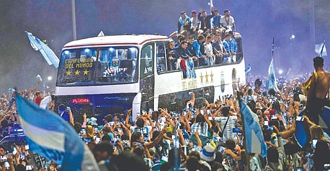 Football fans surround the bus carrying the newly crowned world champion Argentina in Buenos Aires on Tuesday
