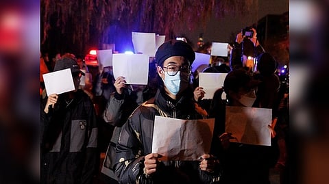 People gather for a vigil and hold white sheets of paper in protest over Covid-19 curbs