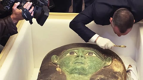 Mostafa Waziri, top official at the Supreme Council of Antiquities, takes a look with a magnifier at an ancient wooden sarcophagus during a handover ceremony at the foreign ministry in Cairo, Egypt.