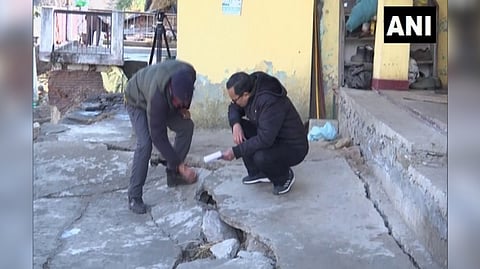 Officials inspect land subsidence by placing a gauge over cracks in subsidence affected area of Joshimath