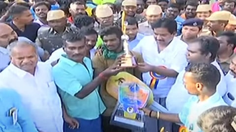 Minister P Moorthy awards the key for the car and gift trophy to Tamilarasan, who secured first place in Palamedu Jallikattu.